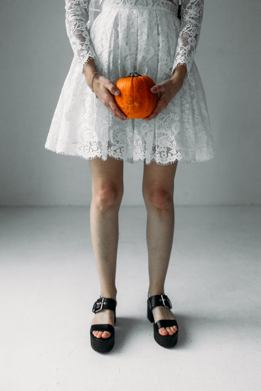 woman in white dress holding a pumpkin