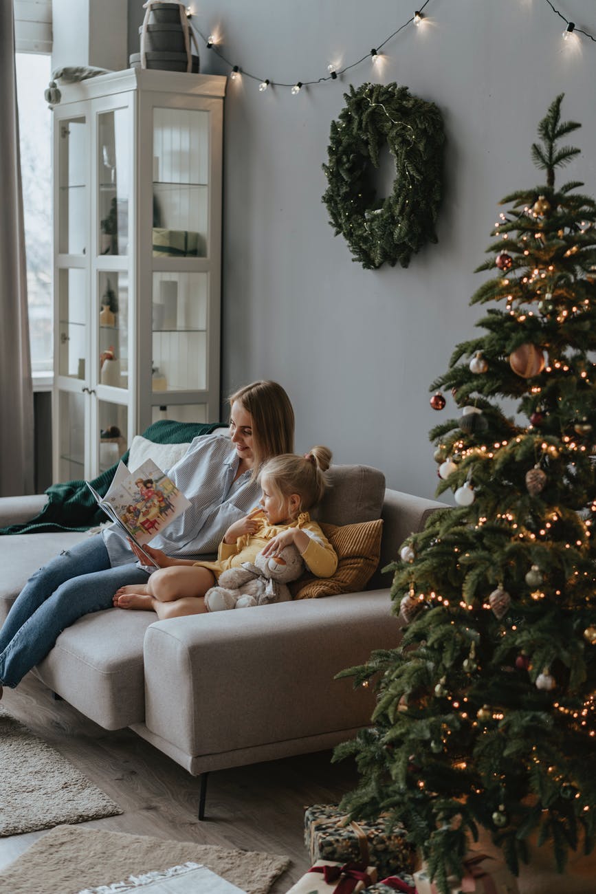 a woman reading book beside her daughter