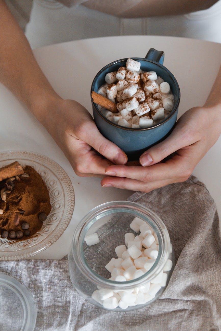 person holding clear glass bowl with white and brown nuts