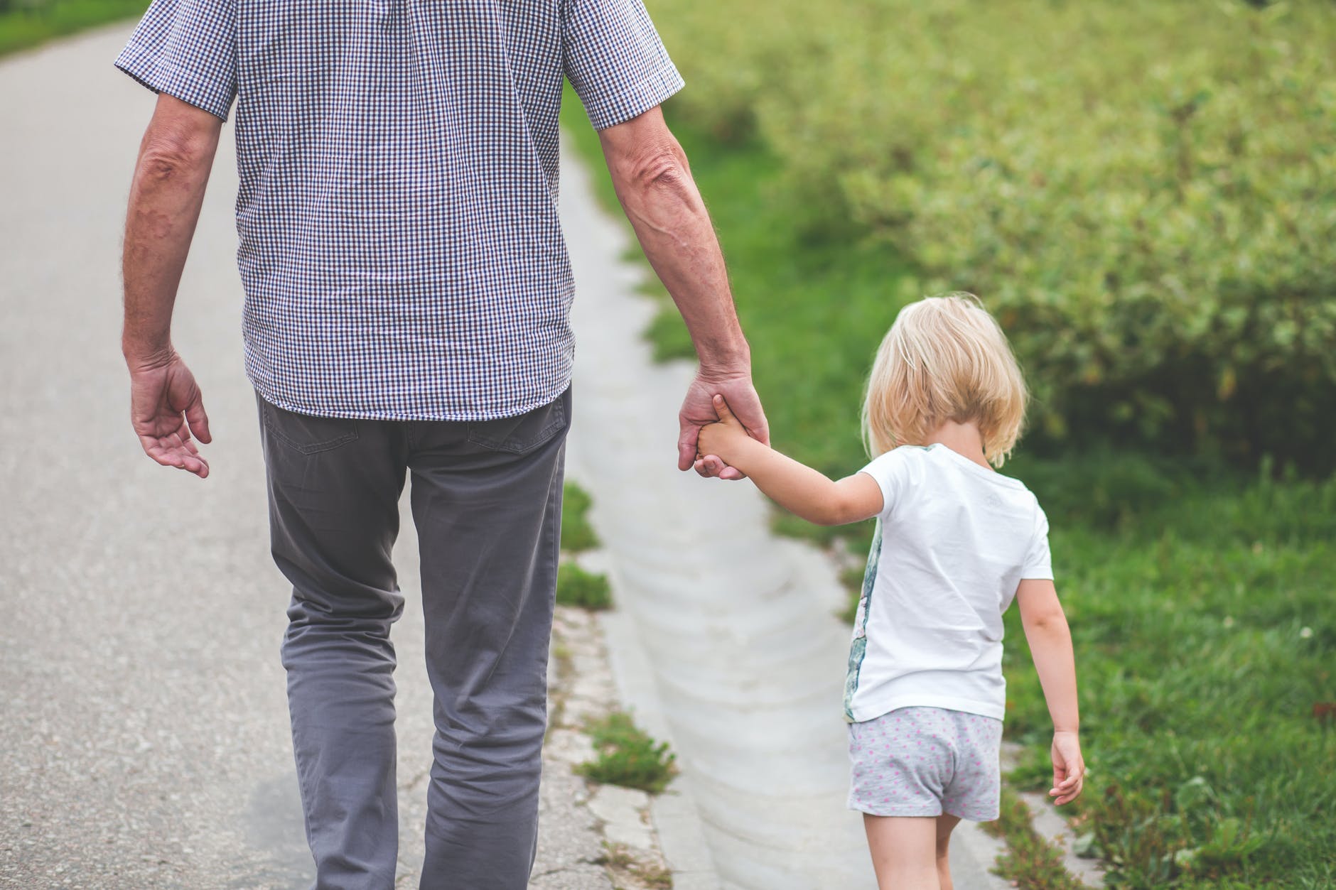 man and child walking near bushes during daytime